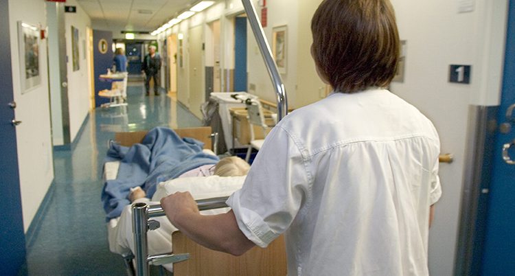 En personal rullar en patient i en säng.