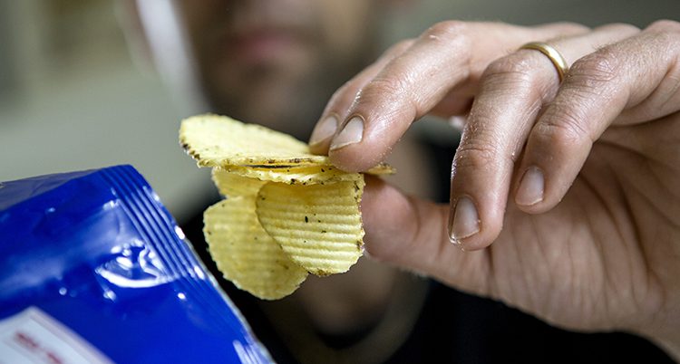 En man äter chips