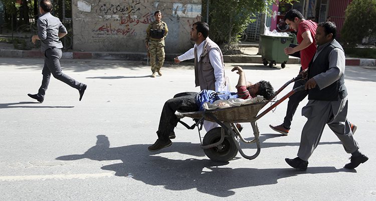 Flera personer kör en skottkärra med en skadad man på en gata i Kabul.