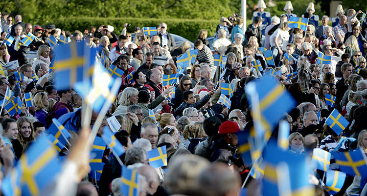 Folk viftar med flaggor på Skansen på nationaldagen.