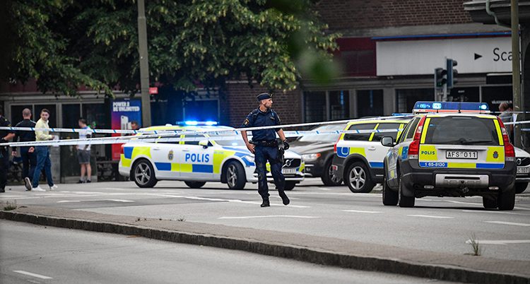 Flera polisbilar och en polis syns bakom en avspärrning.