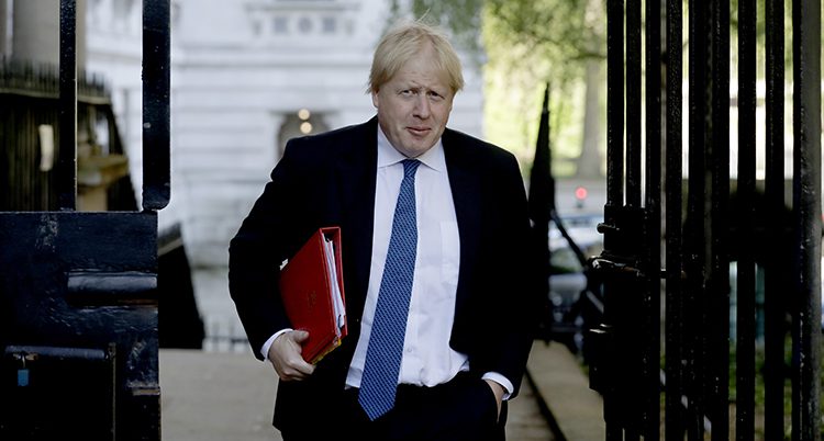 Boris Johnson går med en pärm under armen.