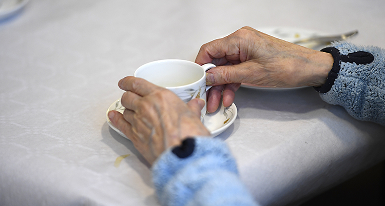 Två händer håller i en kopp kaffe.