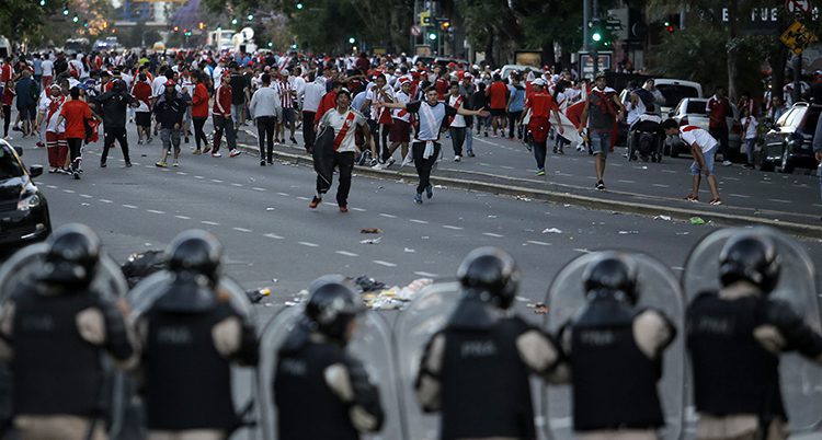Fotbollsfans och poliser bråkar på en gata.