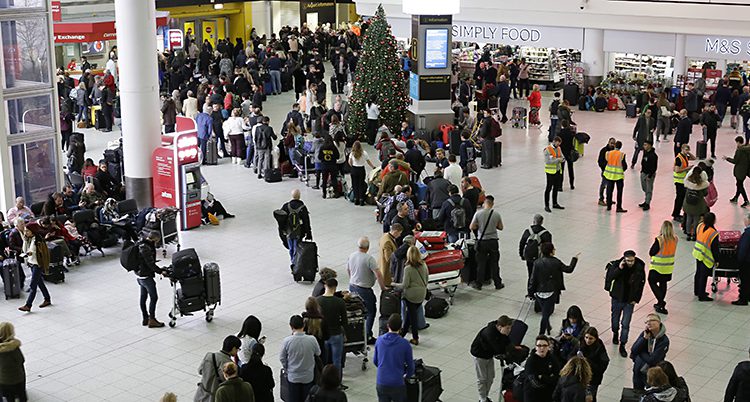 En stor hall i Gatwick full av folk som köar fotad ovanifrån. En julgran finns också mitt i bilden.