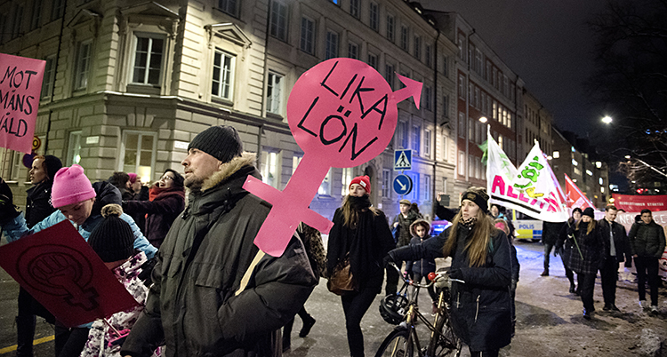 Folk går med skyltar på gatan.