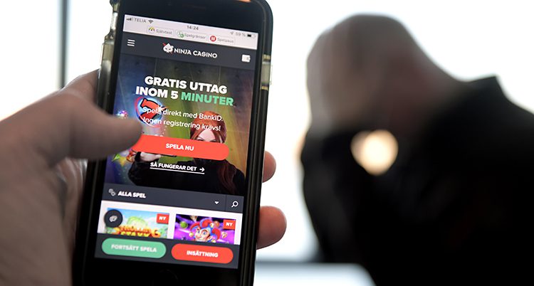 En hand håller i en mobil som visar ett casino på nätet