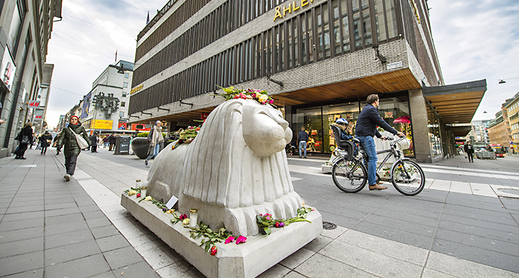 Ett lejon av sten med blommor omkring