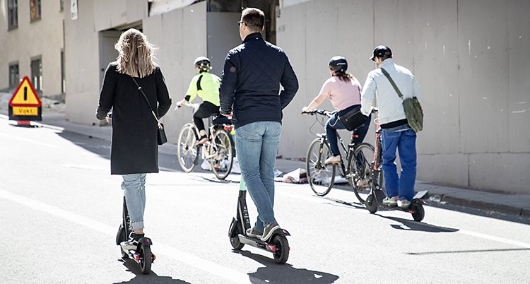 Flera personer åker sparkcykel upp för en backe.