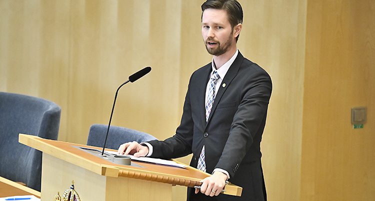 Politikern Rasmus Ling står vid en talarstol i riksdagen.