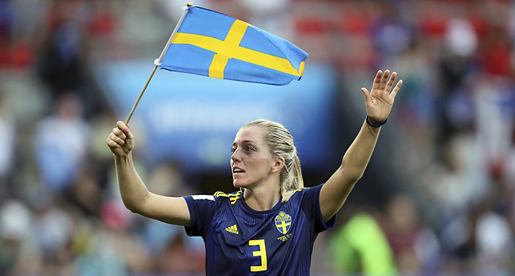 En spelare i fotboll viftar med en svensk flagga.