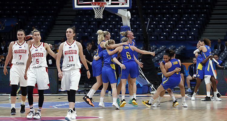 Några svenska spelare kramar varandra på en basketplan. Några ryska spelare ser ledsna ut.
