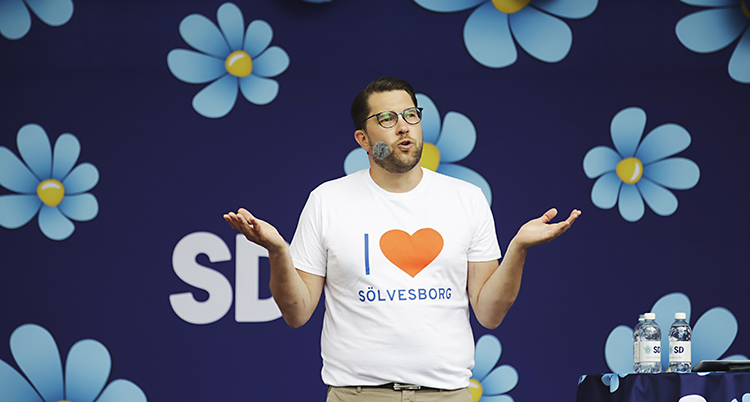 Jimmie Åkesson står på en scen och pratar. Han har en t-shirt där det står "I love Sölvesborg".