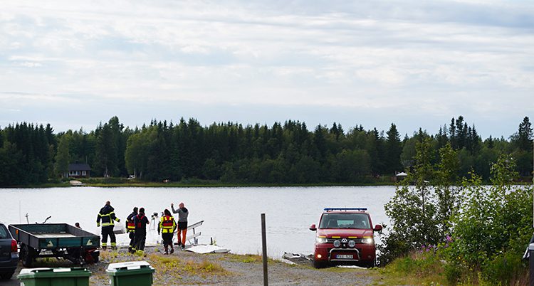 Personal och bilar från räddningstjänsten står vid en strand.