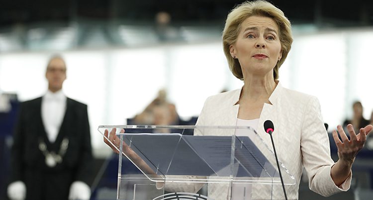 van der Leyen i vitt framför en talarstol. Hon ser nöjd ut.