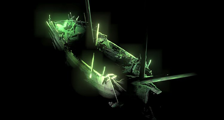 Den gamla båten är upplyst av gröna lampor. Runt om är det svart.