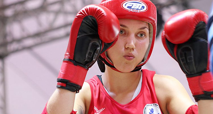 Emma Stonegård Abrahamsson tävlar i thaiboxning. Hon har på sig ett rött linne, ett rött skydd för huvudet och röda handskar.