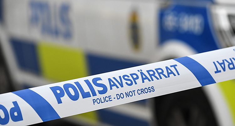 Poliser har spärrat av ett område med ett band. Bakom syns en polisbil.