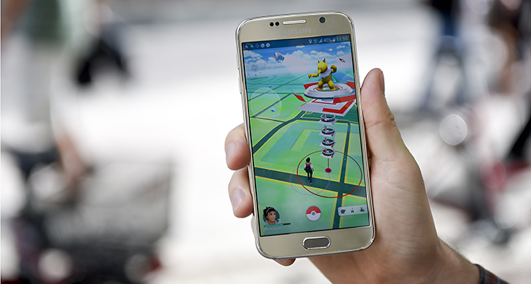 En hand håller upp en mobile med Pokémon Go på skärmen