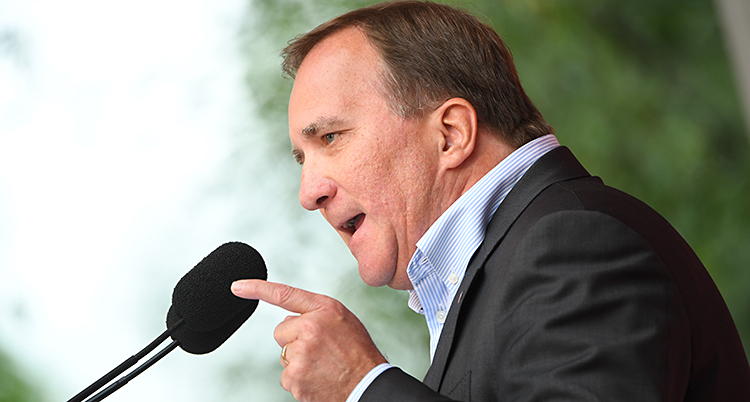 Stefan Löfven i profil framför en mikrofon. Han pekar och ser bestämd ut.