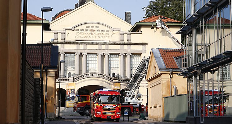 En brandbil står på en gata framför en stor vitt hus som är byggt i gammal stil.