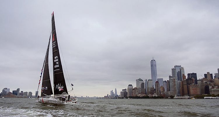 Segelbåten med svarta segel närmar sig New Yorks skyskrapor från havet.