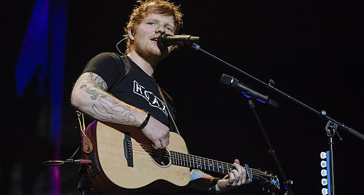 Ed Sheeran spelar gitarr på en scen.