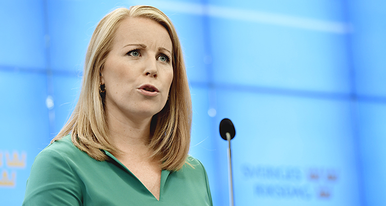 Annie Lööf i grön skjorta framför en mikrofon.