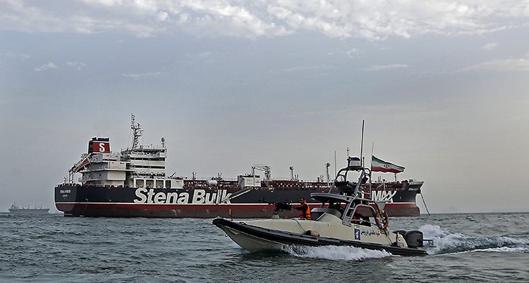 En mindre båt med militärer och iranska flaggor åker runt en stor båt som det står Stena Bulk på.