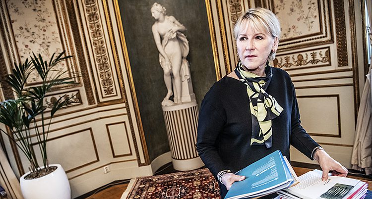 Margot Wallström står vid sitt skrivbord på utrikesdepartementet. Hon fixar med några papper. I bakgrunden syns en staty.