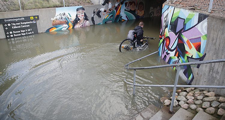 En person bär en cykel genom högt vatten