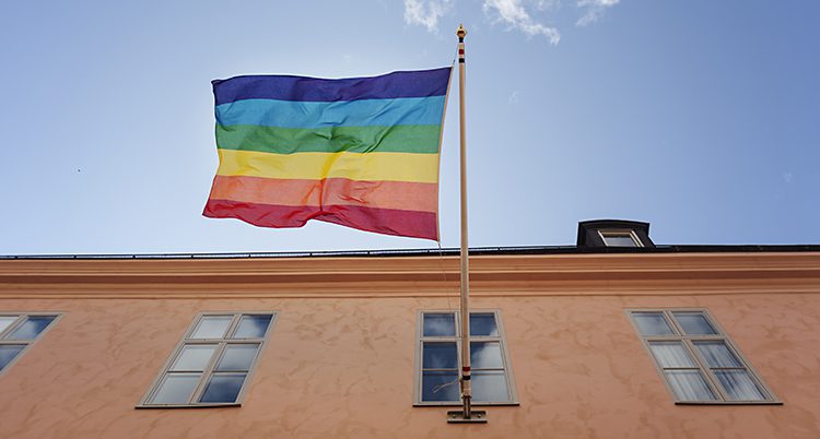 En prideflagga hissad på en stång utanför ett hus.