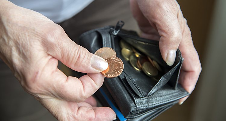 En hand letar bland mynt i en sliten plånbok