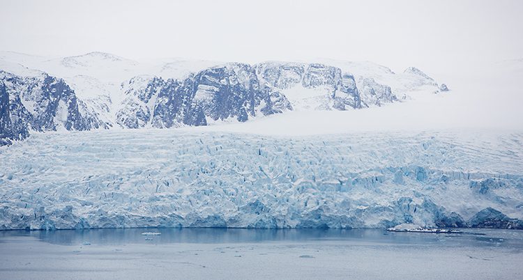 Ett isblock välter i havet på Svalbard.