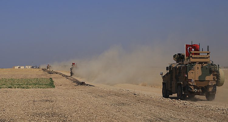 Ett militärt fordon på en dammig ökenväg.