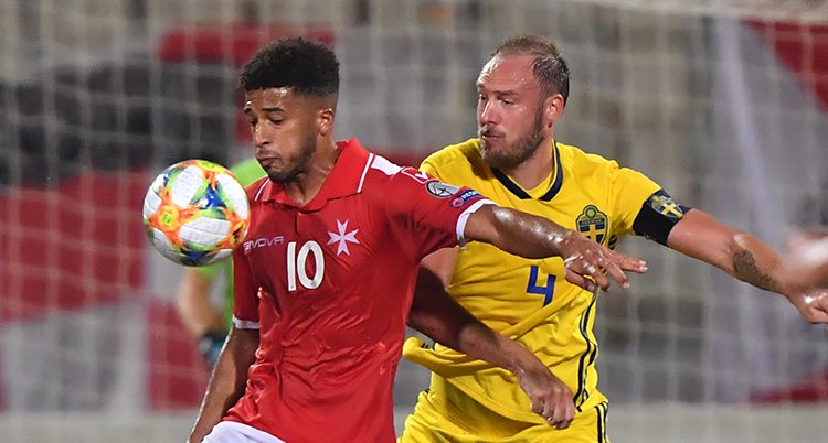 En spelare från Malta har bollen framför bröstet. Andreas Granqvist är bakom honom och försöker att komma åt bollen.