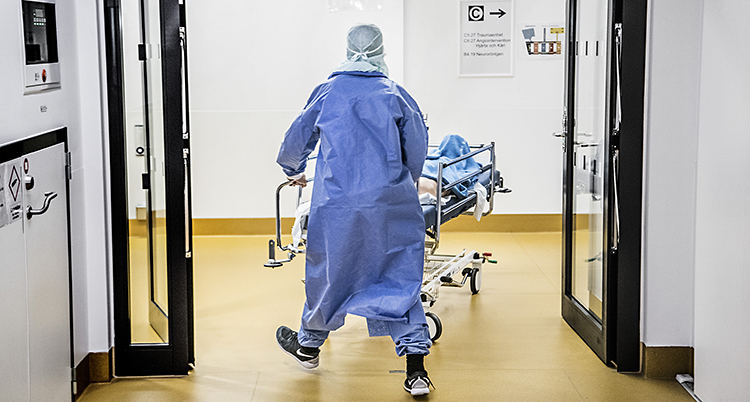 En person i operationskläder drar en sjukhussäng.