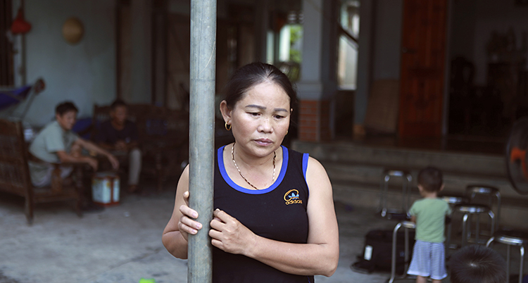 Hoang Thi Ai håller i en stolpe. Hon tittar ner i marken. Hon har ett svart linne på sig.