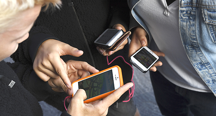 Några barn står i en ring. De håller alla i sina mobiltelefoner.