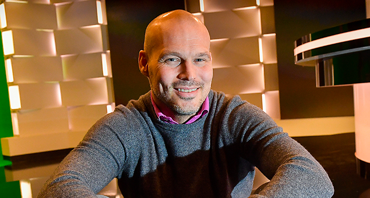 Fredrik Ljungberg sitter i en studio. Han ler mot kameran. Han har rakat huvud och en grå tröja.