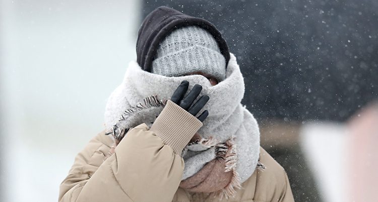 En människar döljer hela ansiktet i mössa och halsduk. Det verkar vara mycket kallt ute