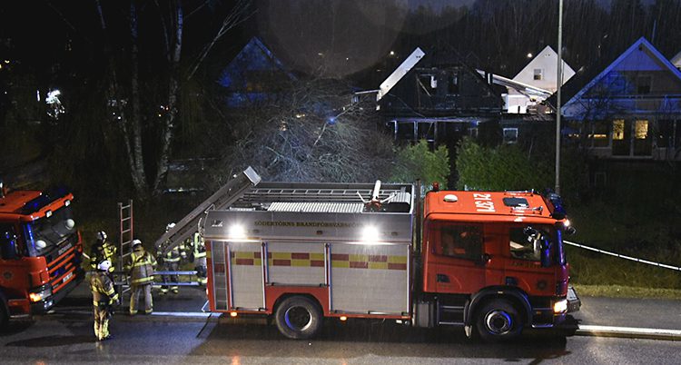 En brandbil på en mörk gata framför ett radhus