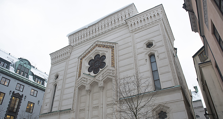 Fasaden av den i sten vita synagogan. Ett vackert bygge med blomformat fönster och mönster som kantar taket.