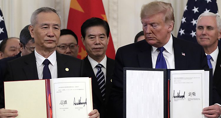 En kinesisk representant och Donald Trump håller upp varsitt avtal. Bakom står tjänstemän och ser nöjda ut.