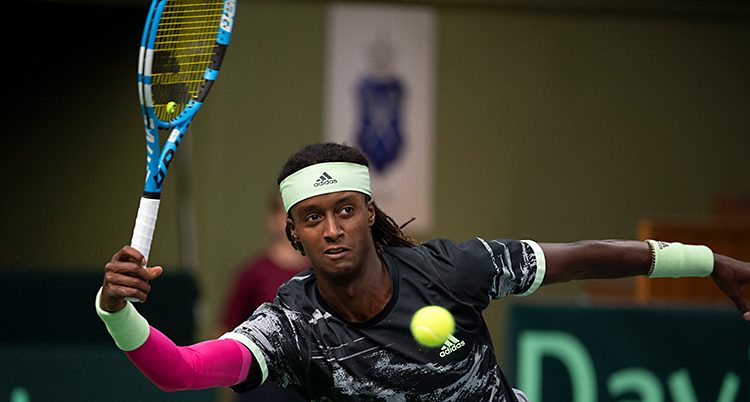 Mikael Ymer spelar en match i tennis. Han har sitt racket i luften och precis framför honom är tennisbollen.