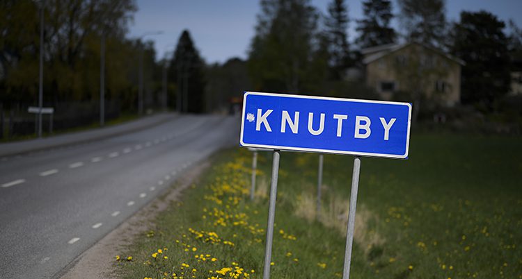 En vägskylt vid en väg. På skylten står det Knutby.