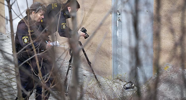 två poliser fotar något på marken utomhus.