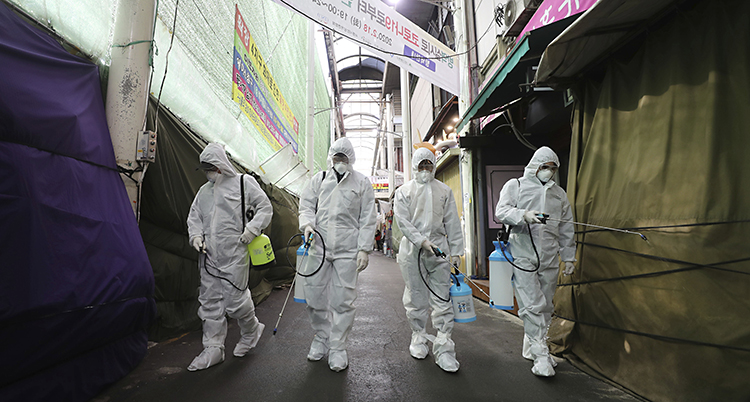Fyra vitklädda personer sprutar sprej på en marknad.