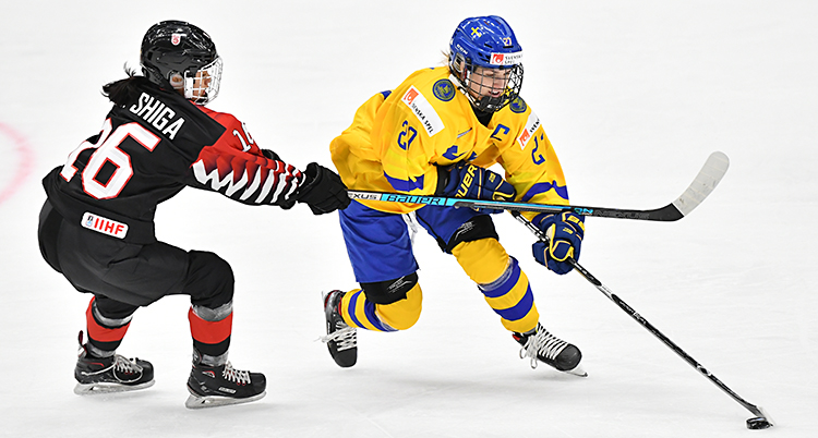 En bild från en match. En svensk spelare dribblar med pucken.