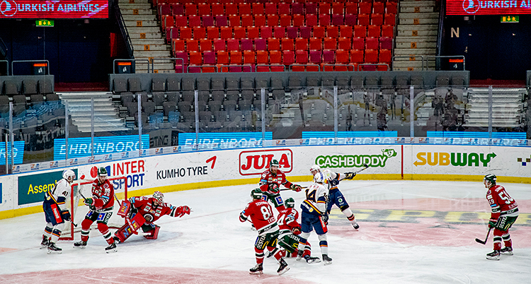 Två lag som spelar en match i ishockey. Det är tomt på läktarna. Ingen publik är där.